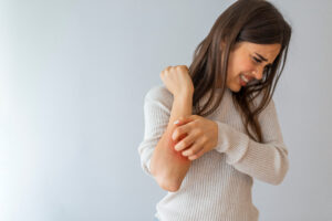 Woman with psoriasis scratching arm